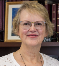 Portrait of Chair Patricia Rankin standing in front of bookcase.